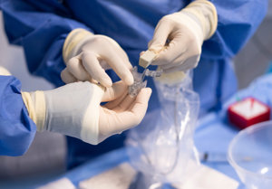 The gloved hands of two interventional radiologists handling medical equipment