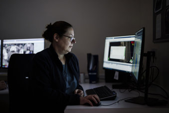 Female oncologist sitting at a desk looking at computer screens.